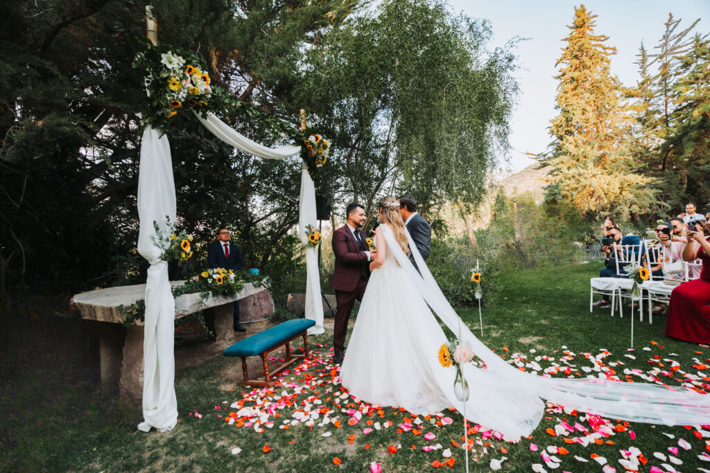 novia caminando hacia el altar decorado con flores en una ceremonia al aire libre en alto de pirque