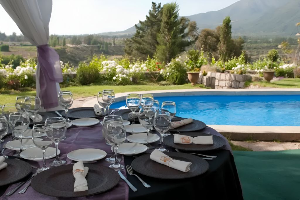 decoración de mesa elegante junto a una piscina con vista panorámica en alto de pirque